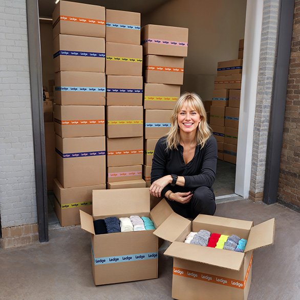 Imagen generada con IA del proyecto de calcetines: fundadora de empresa con cajas de calcetines foto retocada para e-commerce y comunicación visual de producto