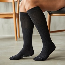 Imagen generada con IA del proyecto de calcetines: mujer sentada en una silla con calcetines negros vista lateral para e-commerce y comunicación visual de producto