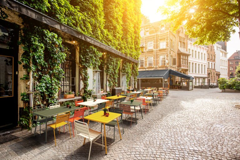 Fotomontaje de imagen mas render 3D de una terraza de una cafetería con mesas y sillas de colores, en un barrio bohemio de parís creada para catálogo y comunicación visual